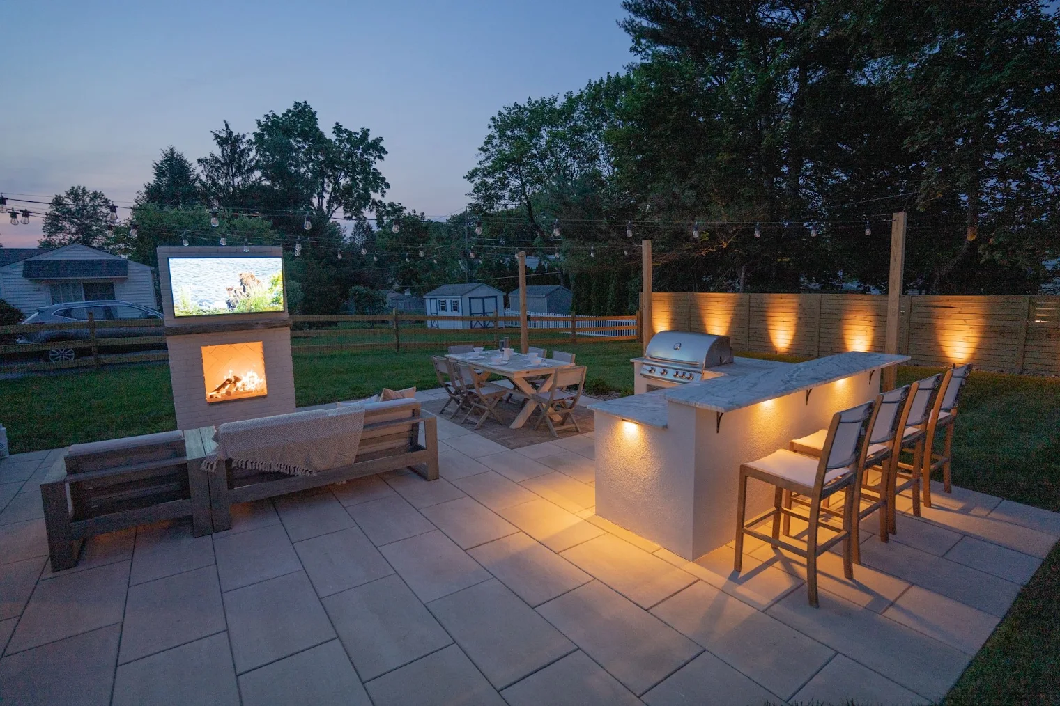 A newly installed Montgomery County patio with a table, chairs, bar seating, grill, fireplace, and TV.